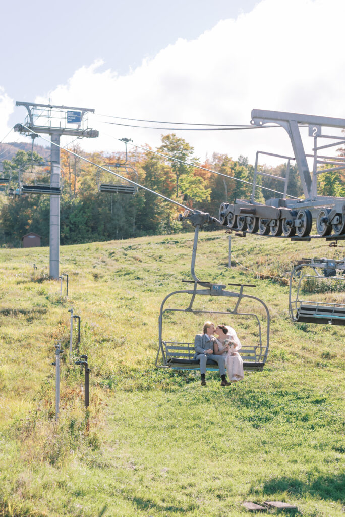 Bride and groom kissing on a chair lift at Sugarloaf USA ski resort in Maine during the summer