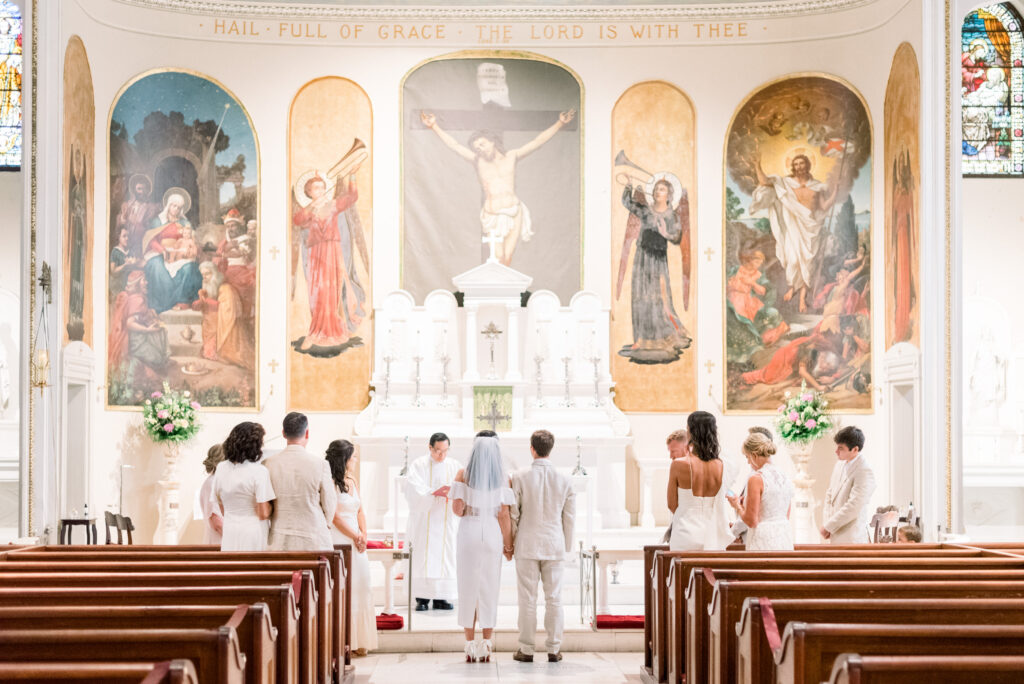 Bride and groom standing arm in arm at the alter during their high fashion catholic chapel elopement micro wedding