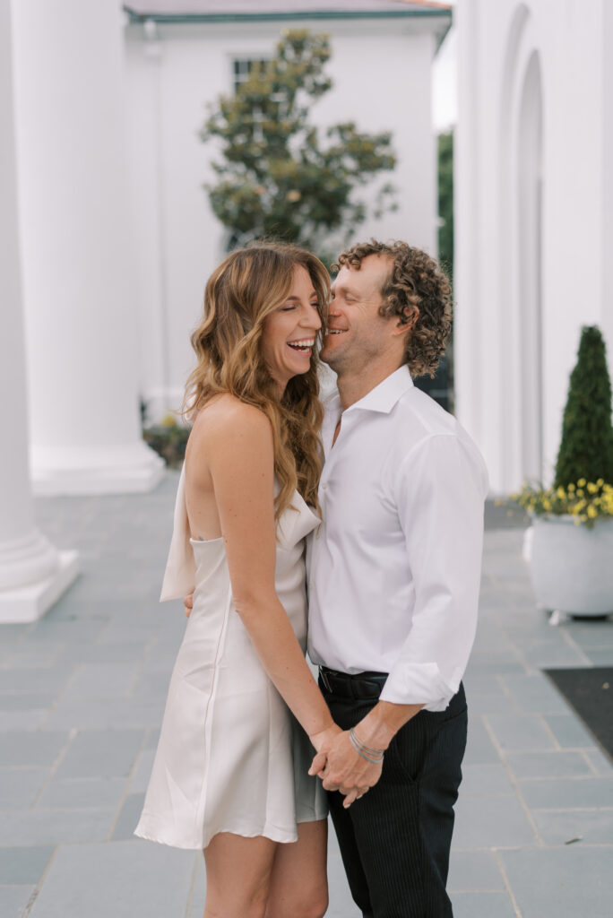 engaged couple holds hands and laugh together