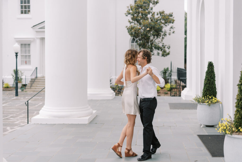 engaged couple dance together on a white church porch in Charleston South Carolina