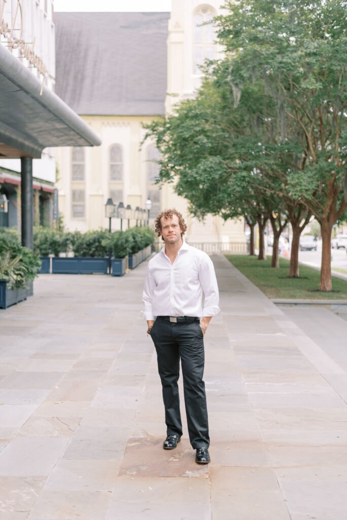 portrait of a man in front of the Dewberry wearing black slacks and a white button down shirt