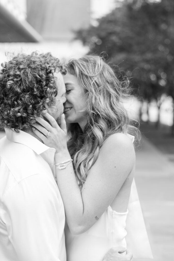 Black and white portrait of an engaged couple kissing