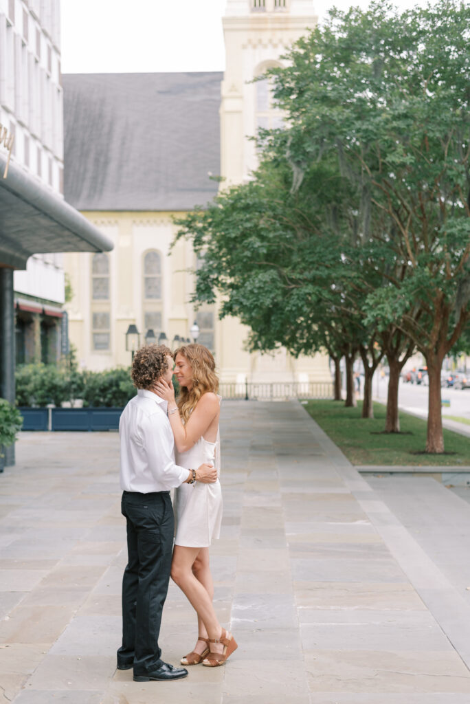 engaged couple kissing on the sidewalk in front of The Dewberry