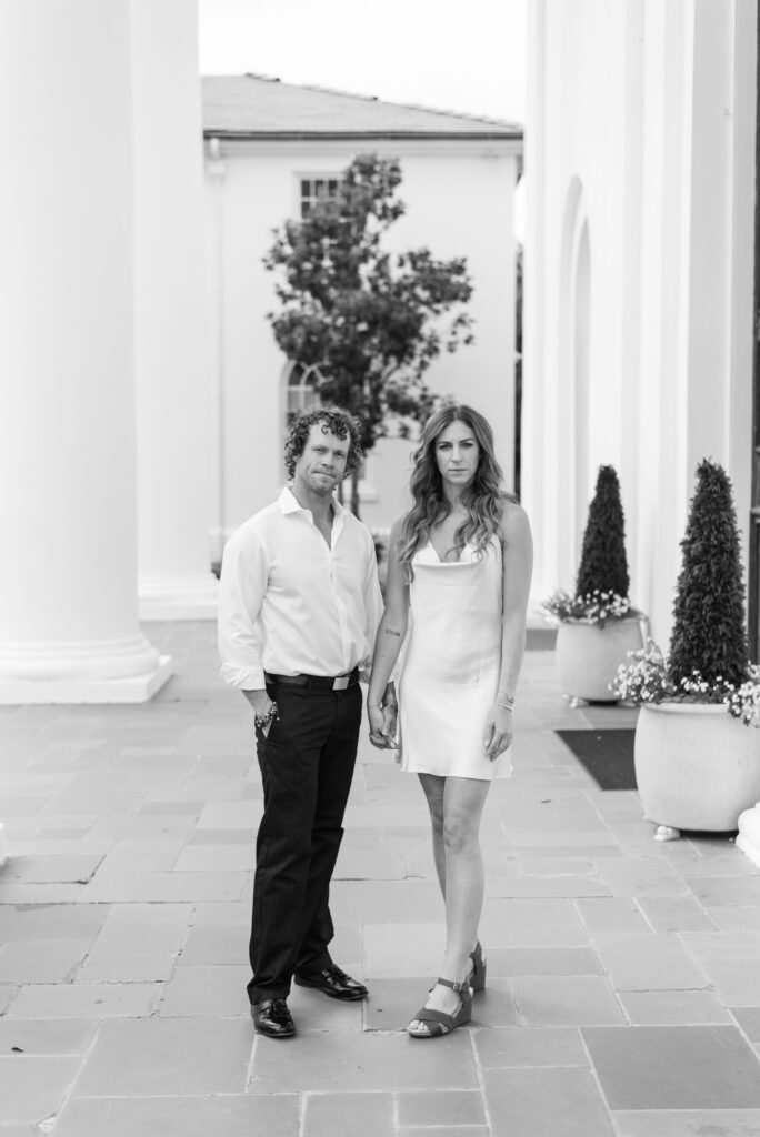 black and white portrait of an engaged couple holding hands and looking straight at the camera