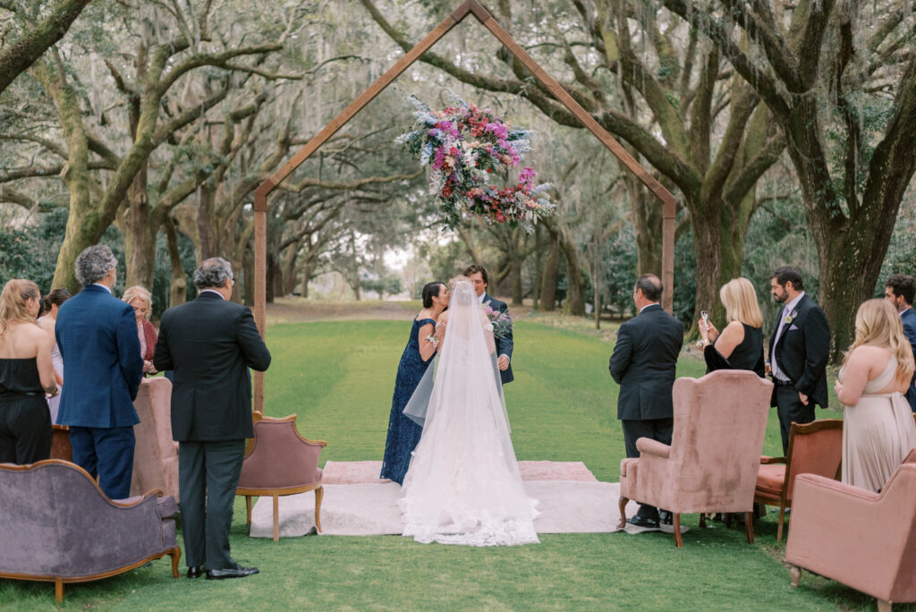 Mother kisses her daughter on the cheek at the top of the aisle during her wedding ceremony