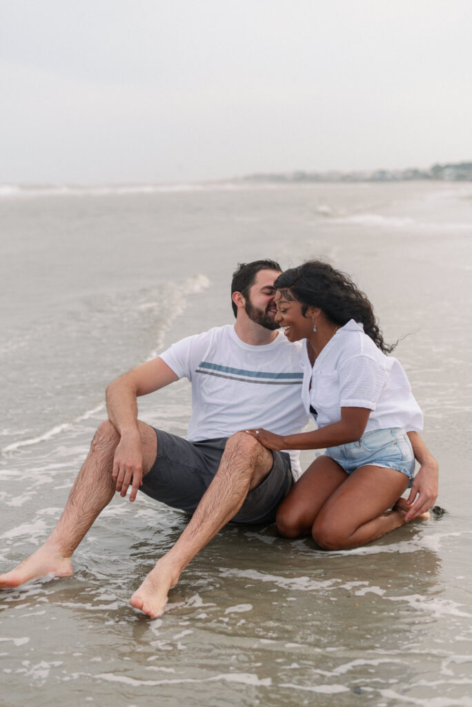 Couple sitting in the water laughing with each other on Isle of Palms