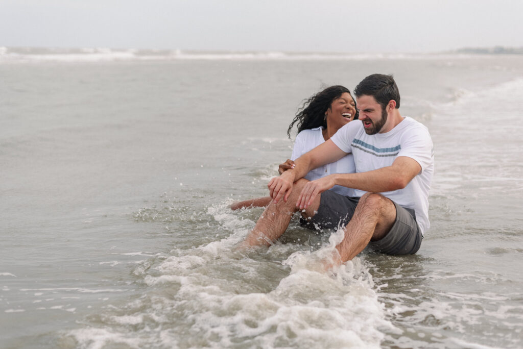 couple getting splashed by a wave and making faces