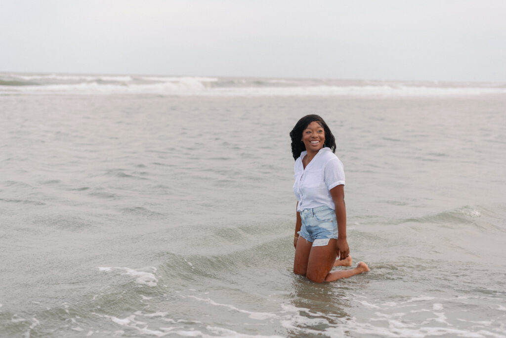 Woman laughing at her partner while she kneels in the waves