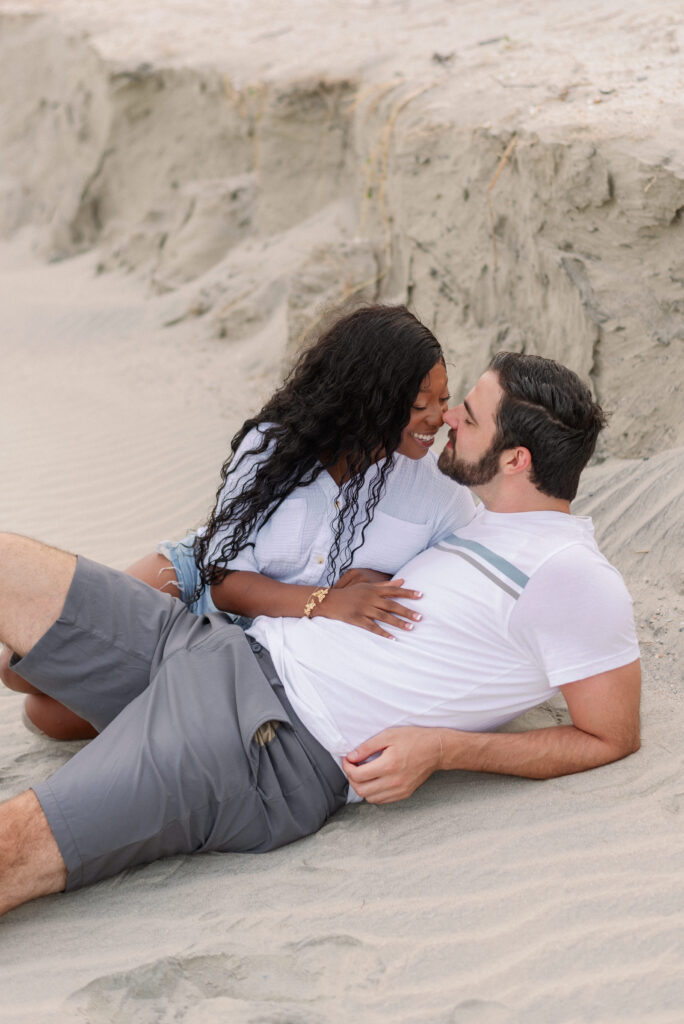 couple lying in the sand and smiling nose to nose