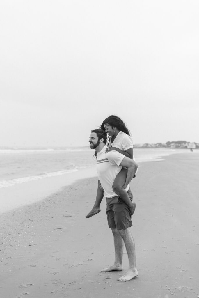 engaged couple with her on his back captured in black and white