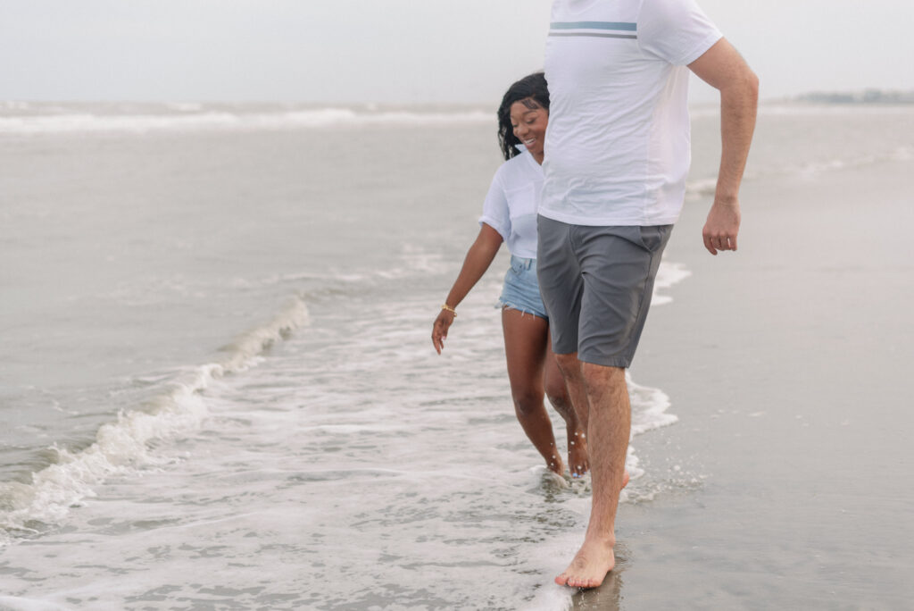 Couple running together through the water on isle of palms beach