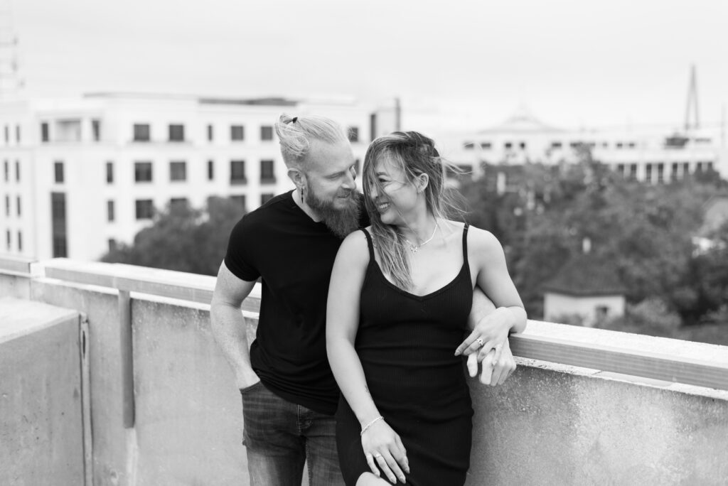 black and white image of a couple laughing at each other while leaning against each other