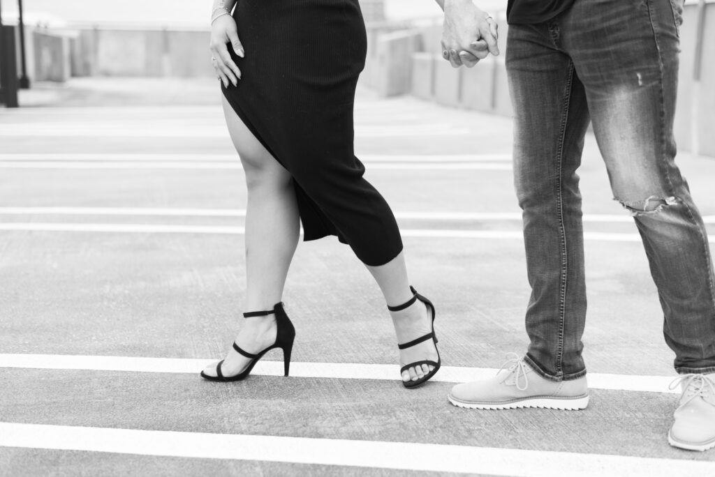 black and white close up of a couple's legs as they walk. Woman is wearing black strappy stilettos' 