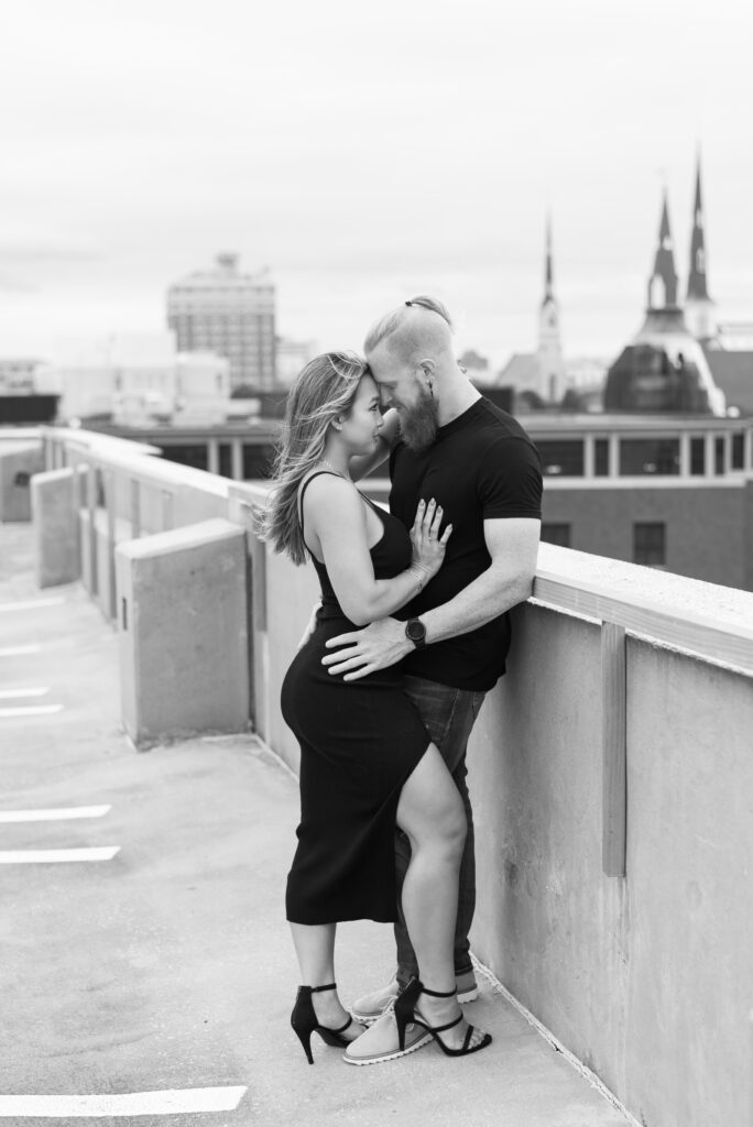 Couple standing in an embrace overlooking downtown charleston captured in black and white