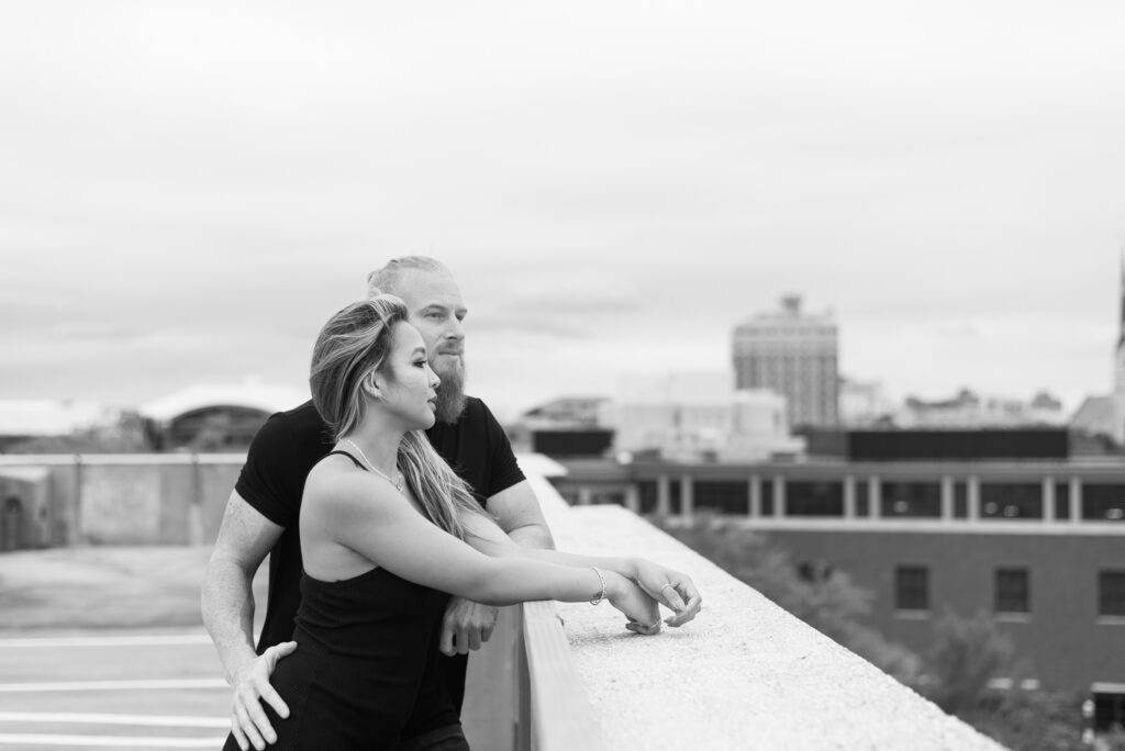 Couple leaning on the parking garage wall and looking out across downtown Charleston