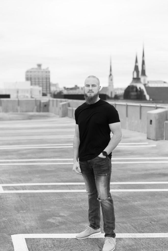 Man in a black shirt and jeans standing on top of a parking garage