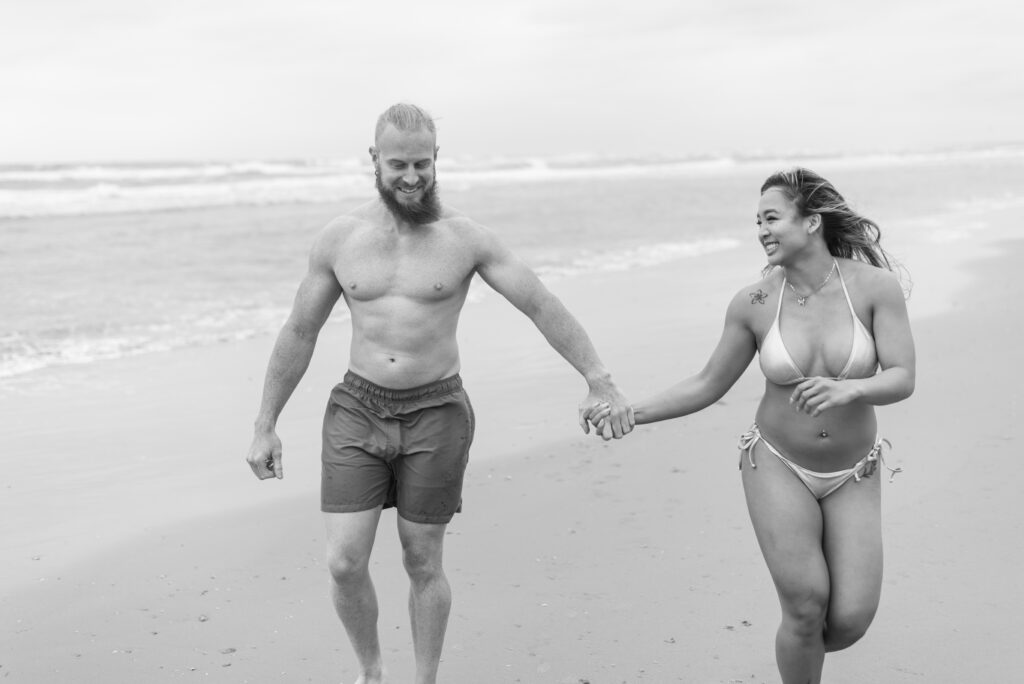 couple laughing and walking down the beach together