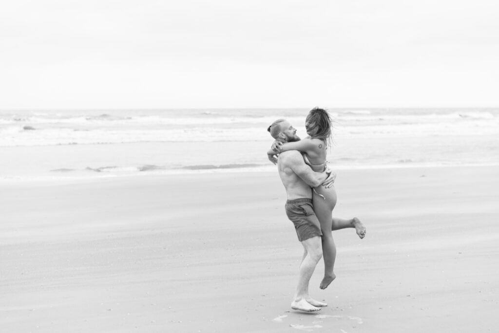 man holding his girlfriend and spinning her around while they laugh captured in black and white