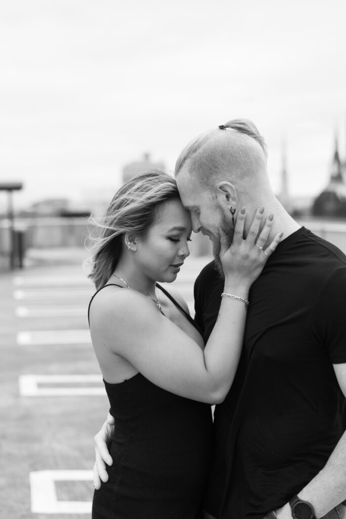 black and white image of a couple standing forehead to forehead with their eyes closed