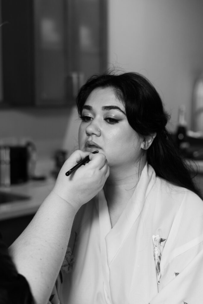 A woman has her lips done by a professional makeup artist on her wedding day