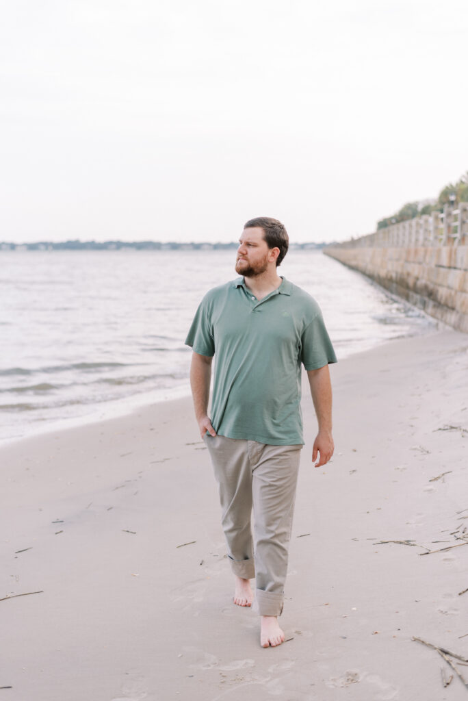 a man walking on the beach in a green polo and khakis