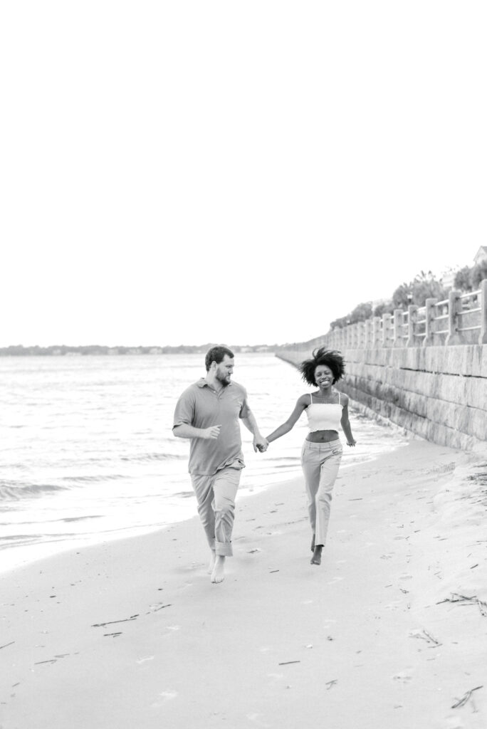 Couple laughing and running on the beach at the Charleston Battery