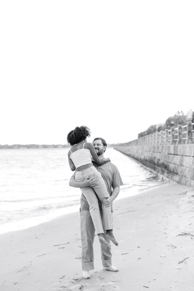 man picks his girlfriend up on the beach in downtown Charleston