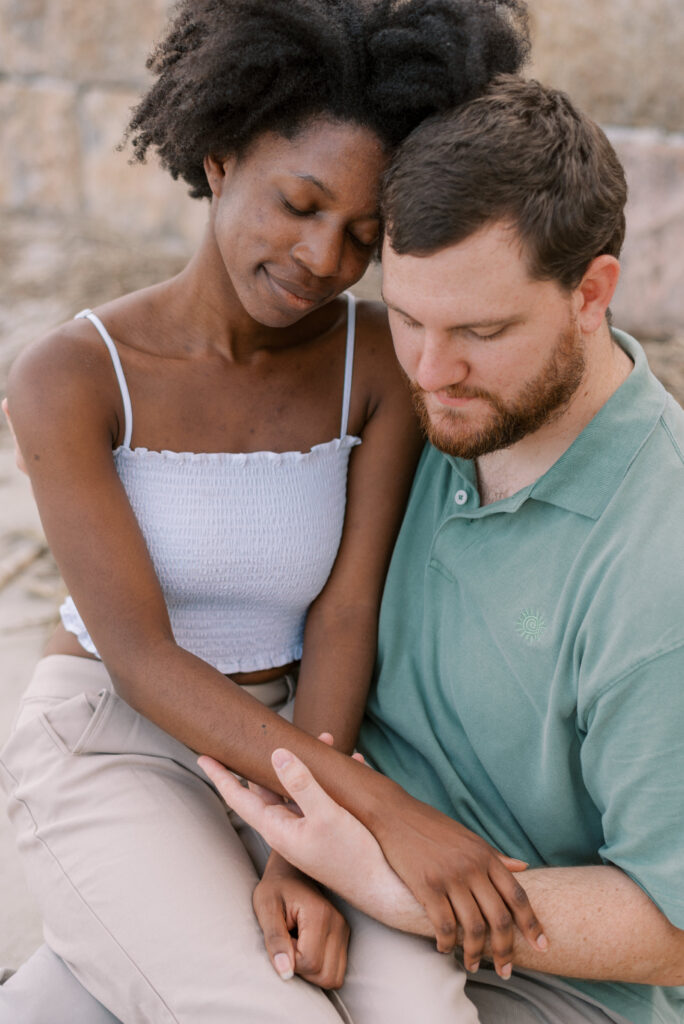 Couple sit together with eyes closed and hold hands showing their beautiful different skin tones