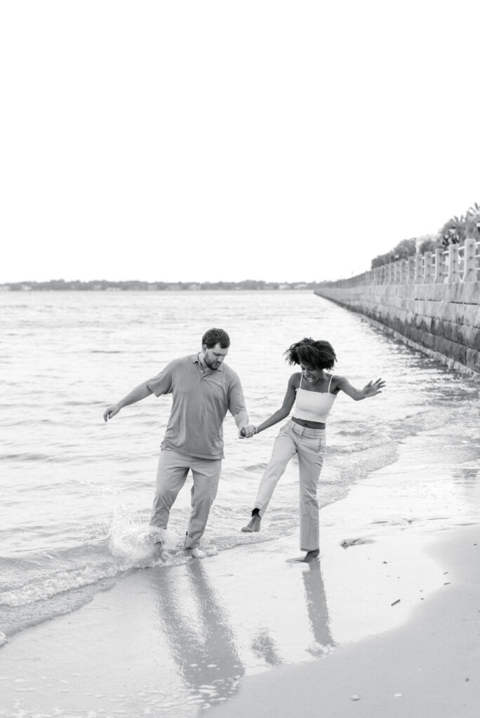 couple walk through the water and hold hands