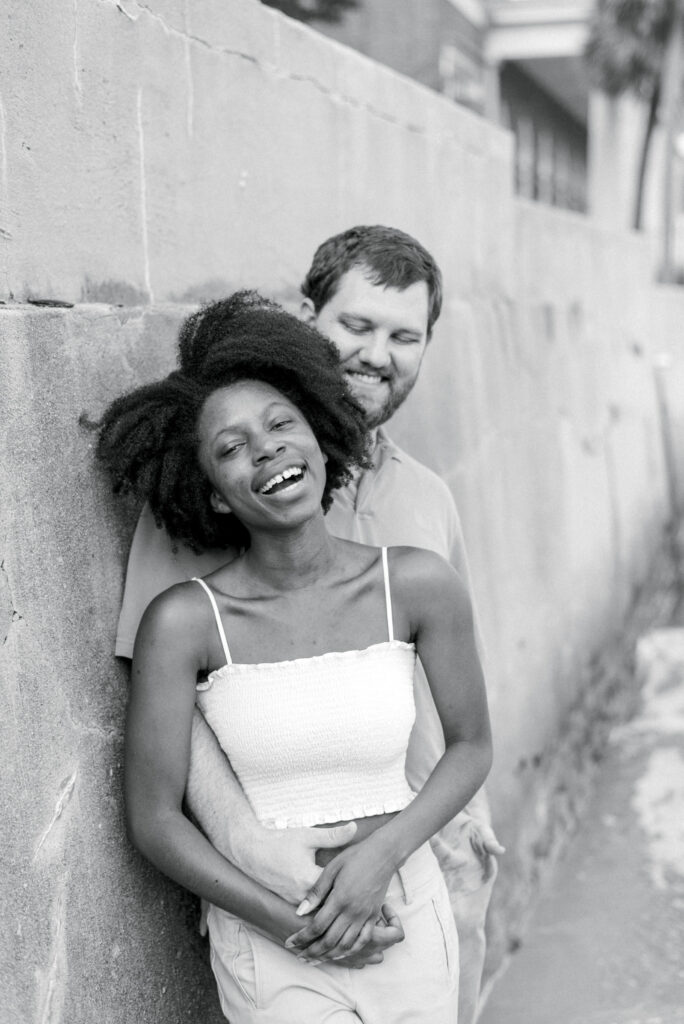 close up of a woman laughing leaning against the Charleston battery wall