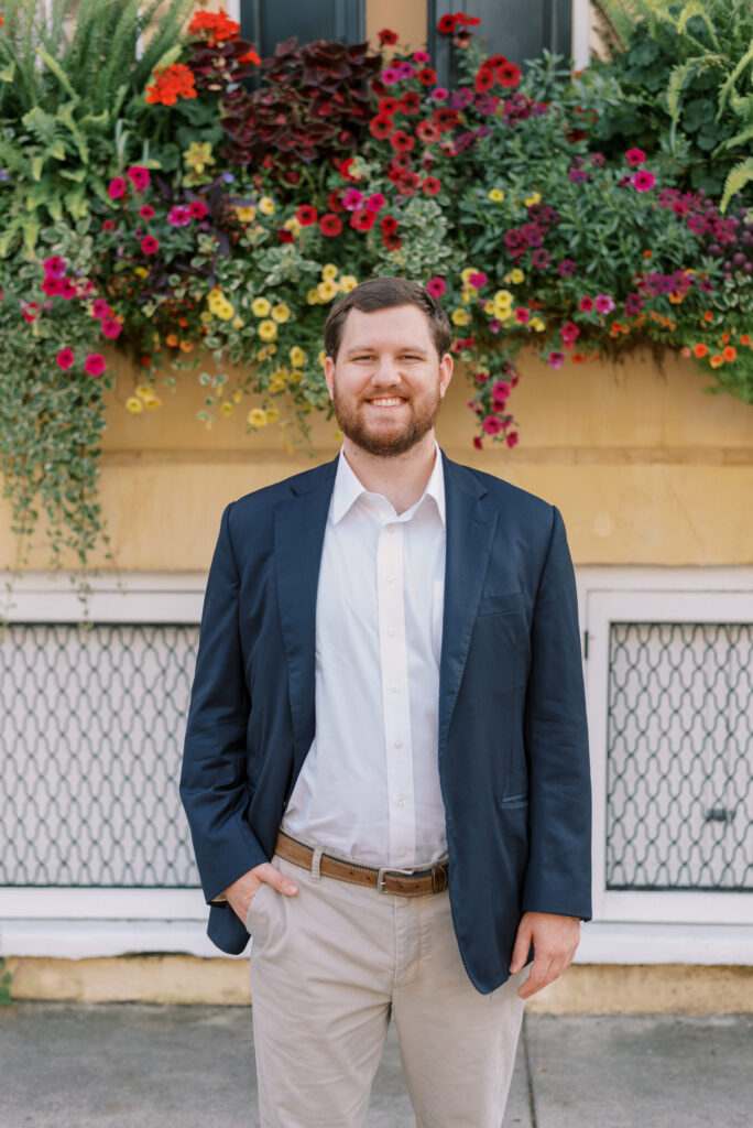 Headshot of a man smiling in front of a yellow house in Charleston