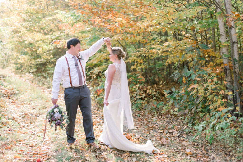 Bride and groom dance together in the fall leaves in Maine