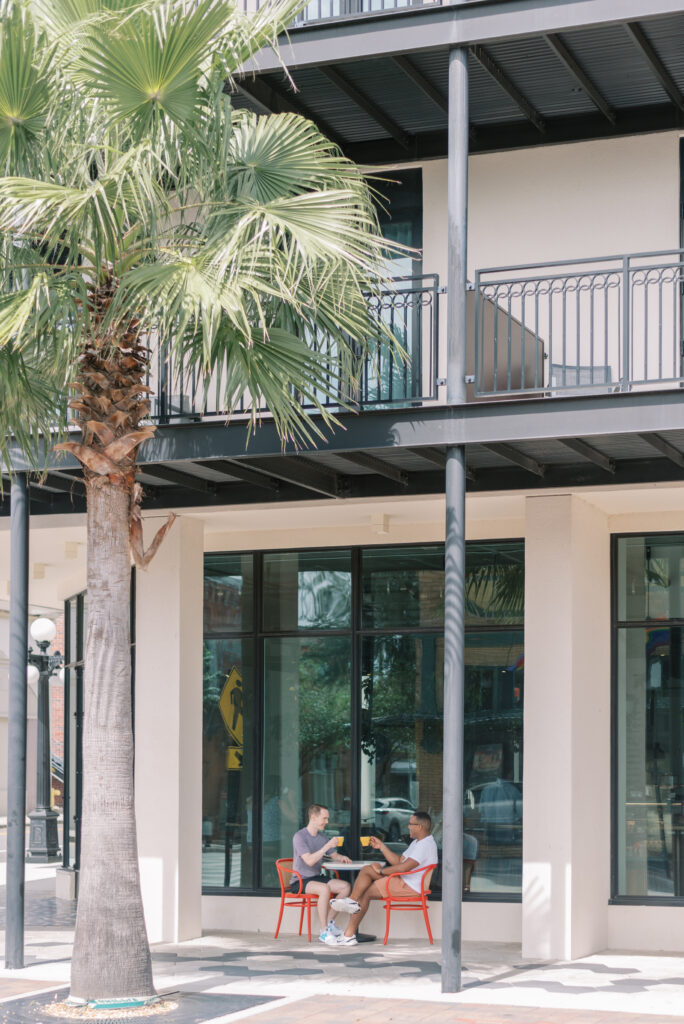 Two grooms sit at a sidewalk cafe in Ybor city and share coffee together on their wedding day