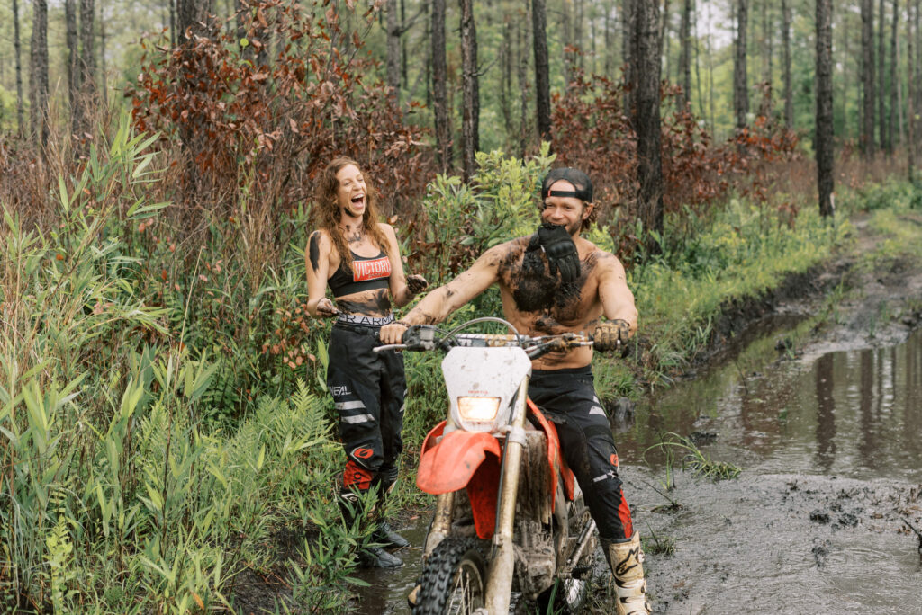 woman laughs at her boyfriend after throwing mud at him in the woods