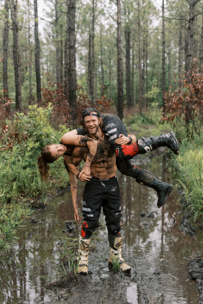 man throws his girlfriend over his shoulder during their woods engagement shoot