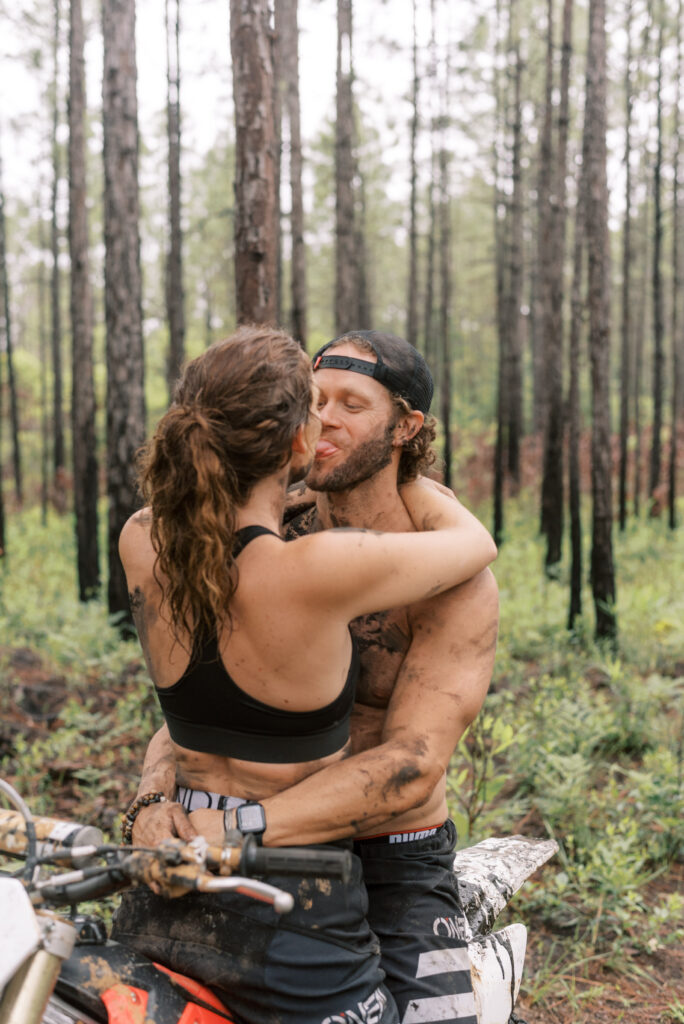 Couple being silly while she sits on his lap on his dirt bike