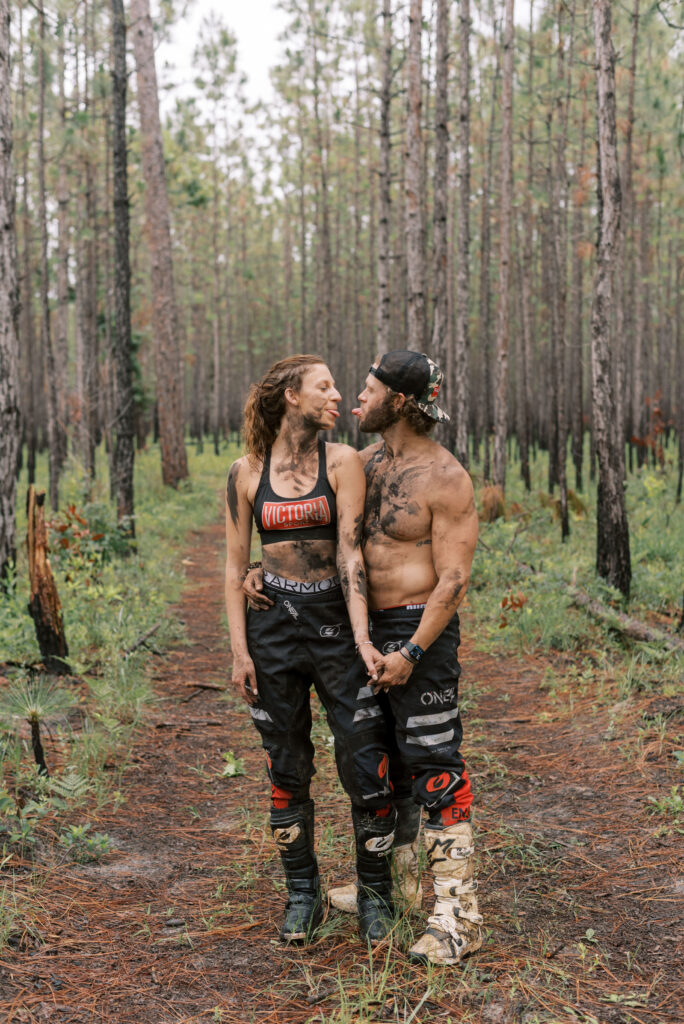 Couple stick their tongues out at each other while holding hands and leaning against each other