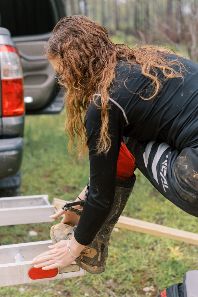 Woman with her foot on a truck rack putting on oneil dirt bike boots in the rain