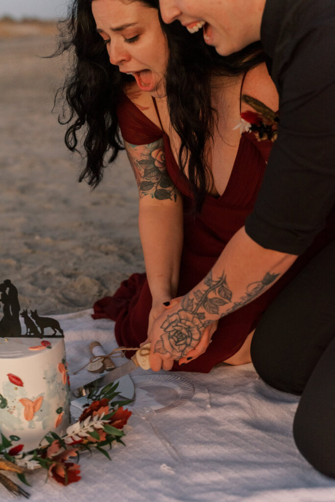 gay couple cut their wedding cake at the beach during their elopement