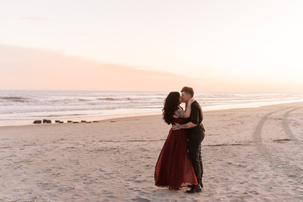 brides kiss on the beach at sunset after their elopement ceremony