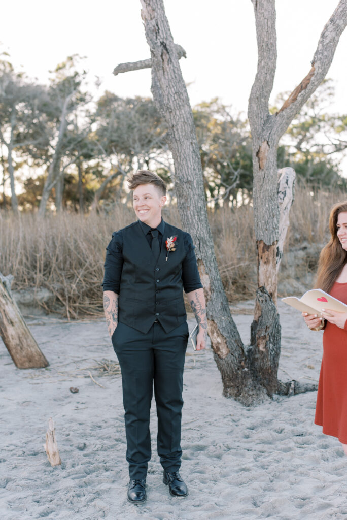 Bride smiles as her bride walks towards her on the beach