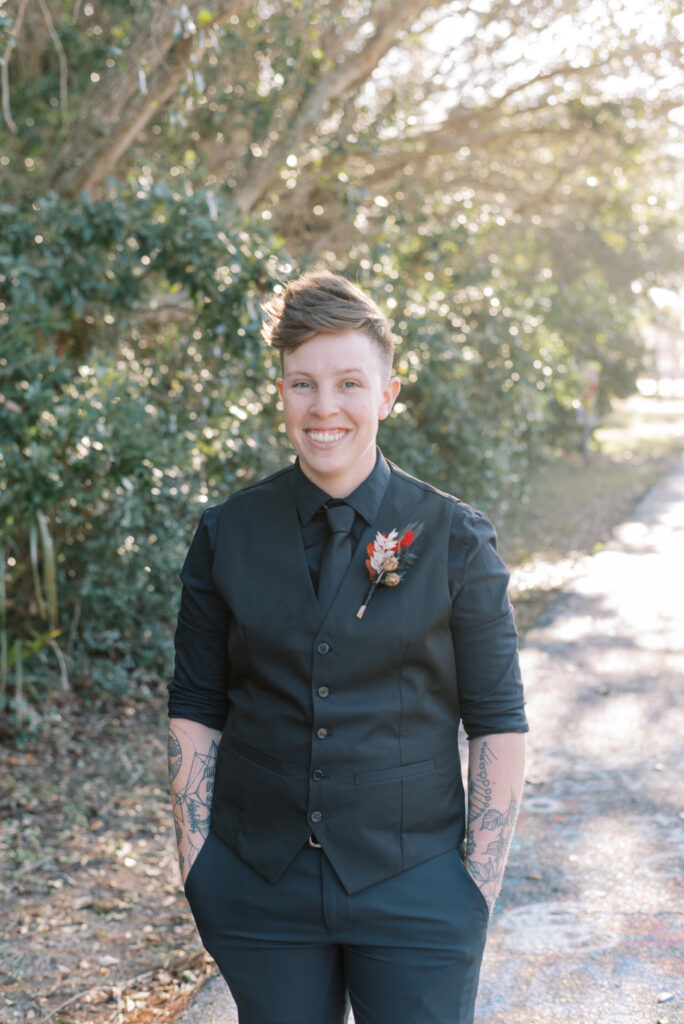 Woman in a black vest and slacks with a boutonniere before her elopement