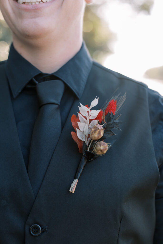 Close up of boutonniere with dried flowers red white and black