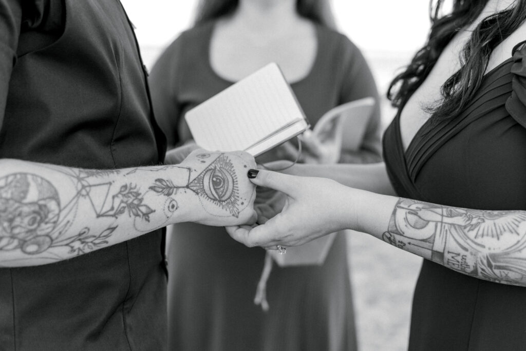 Close up of two brides exchanging vows, tattooed arms and hands