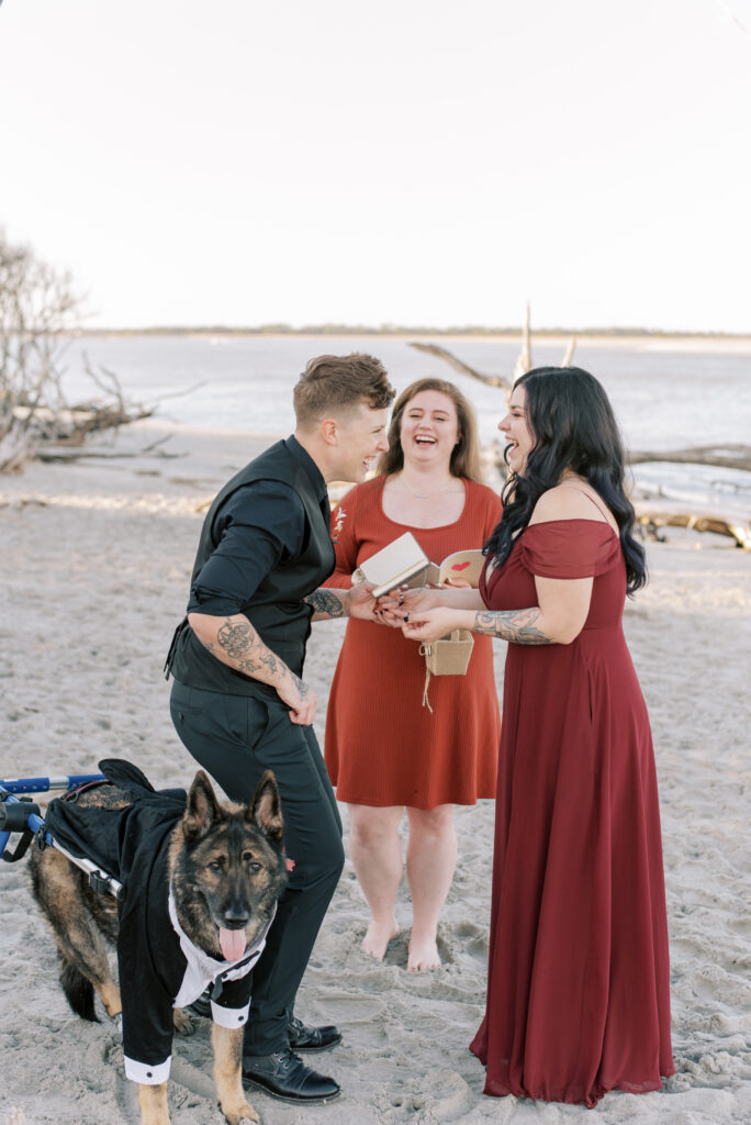 Two brides laugh at each other during their elopement ceremony on the beach